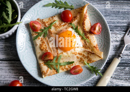 Crêpes avec des œufs, du fromage, de roquette et de tomates.Galette complète. Plat traditionnel galette sarrasin Banque D'Images