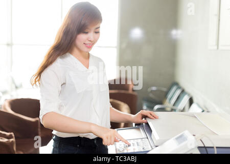 Belle femme asiatique de l'imprimante via in office Banque D'Images