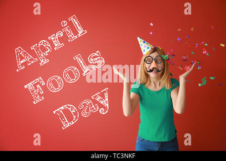 Femme drôle avec décor parti et confettis sur un fond de couleur. April Fools' day celebration Banque D'Images