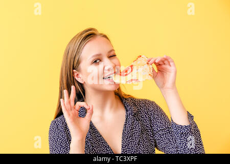 Beautiful woman eating pizza savoureuse sur un fond de couleur Banque D'Images