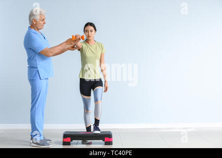 Travailler avec un physiothérapeute mature Young Asian Woman in clinic Banque D'Images