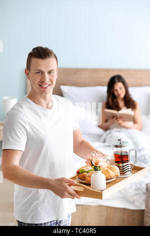 Jeune femme qui reçoit un petit déjeuner au lit de son mari bien-aimé Banque D'Images