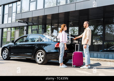 Cheerful woman femme heureuse en étant debout près de rose et voiture assurance Banque D'Images