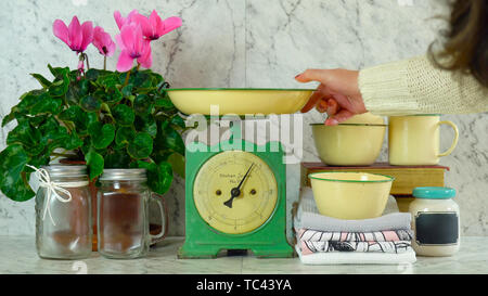 Balance de cuisine vintage avec décor de style ferme ustensiles, avec de vieux livres, des bocaux Mason, vintage tin vaisselle et cyclamens rose en pot. Banque D'Images