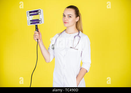 Concept médical de belle jeune femme médecin en blouse blanche avec phonendoscope et lumière noire. Travailleur de l'hôpital femme looking at camera Banque D'Images