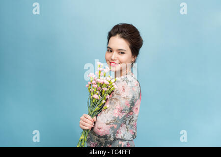 Belle jeune Aisa girl holding a bouquet sur fond bleu Banque D'Images