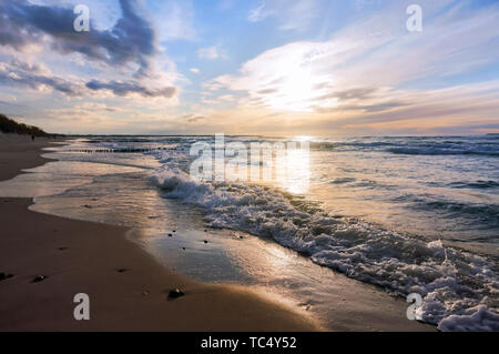 Coucher de soleil sur la mer. Reflet de la lumière du soleil dans les vagues de la mer. Ciel rouge dans les rayons du coucher du soleil. Banque D'Images