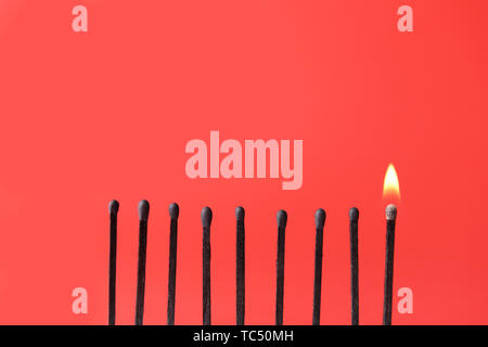 Un match brûlant parmi celles incendiées sur un fond de couleur. Concept de l'unicité Banque D'Images