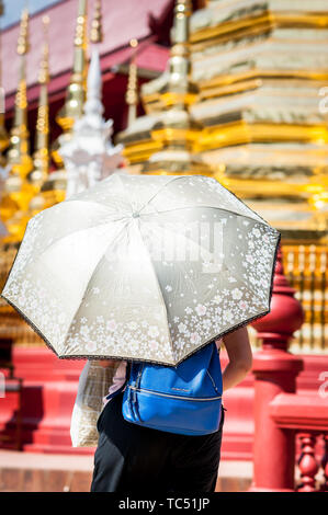 Une femme thaïlandaise tient un parapluie pour se protéger du soleil au Temple Wat Phra Sing, Chiang Mai, Thaïlande. Banque D'Images