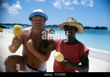 Der Deutsche Sänger Klaus Baumgart posiert mit einheimischen Obstverkäufer vermutlich im Urlaub auf den Bahamas am Strand, ca. Er des années 1970. Le chanteur allemand Klaus Baumgart pose avec un vendeur de fruits locaux en vacances aux Bahamas sur probablement sur la plage, à propos des années 1970. Banque D'Images