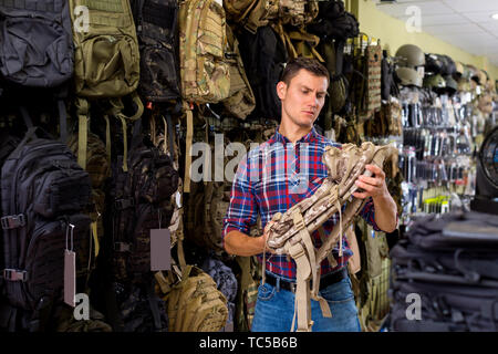 Serios jeune mâle choix client sac camouflage dans la boutique d'airsoft Banque D'Images