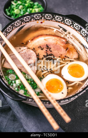 Nouilles Udon à la Soupe de Ramen japonais avec du porc, Œufs et Scallion sur fond sombre Banque D'Images