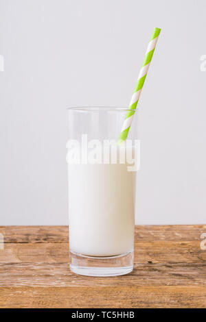 Un verre de lait et un papier rayé vert paille sur la table Banque D'Images