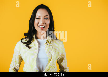 Attractive brunette fille asiatique avec un clin d'isolé sur le jaune Banque D'Images