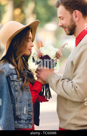 Bel homme à la copine à des fleurs odorantes dans hat Banque D'Images