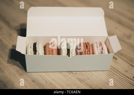 Close up of peu macrons dans une boîte de papier sur une table en bois Banque D'Images