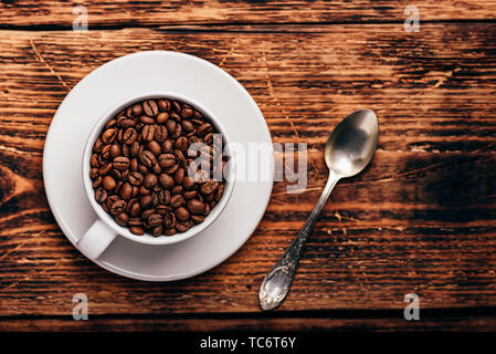Les grains de café torréfiés tasse blanche en plus de surface en bois rustique Banque D'Images