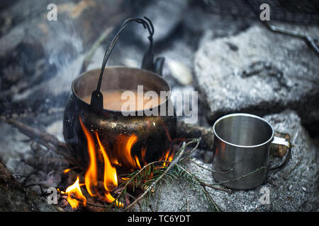 Thé au lait cuit à la mise. Une bouilloire, une tasse en métal, un incendie. Petit-déjeuner du voyageur Banque D'Images