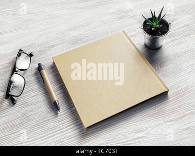 Photo de vide fermé sketchbook, lunettes, stylo et plante sur fond de table en bois clair. Modèle vierge. Banque D'Images