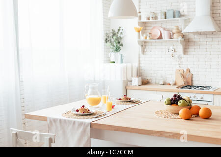 Table servi avec des crêpes, fruits et jus d'orange dans la cuisine Banque D'Images