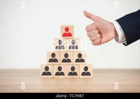 Portrait de man showing thumb up près de pyramide de cubes en bois on white Banque D'Images