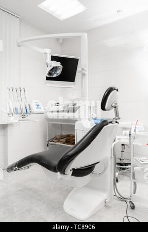 Vue verticale d'un dentiste avec siège noir. Pratique dentaire moderne. Fauteuil dentaire et d'autres accessoires utilisés par les dentistes Banque D'Images