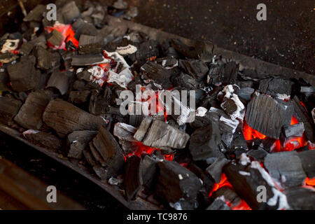 La combustion des charbons ardents et lumineux en bois barbecue fosse. Flaming éclatante et d'un charbon, barbecue, feu rouge et des cendres. Week-end d'arrière-plan des loisirs. Close-up Banque D'Images