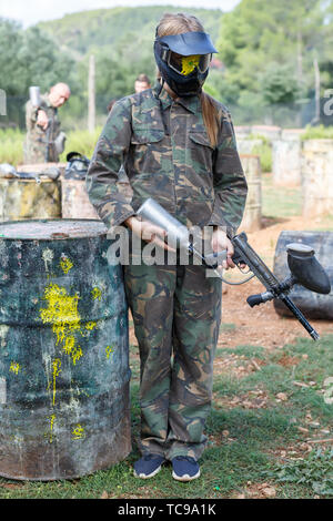 Portrait de femme déçu en casque de protection avec splash après coup direct au jeu de paintball Banque D'Images