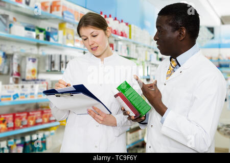 Les jeunes hommes et les femmes expérimentés les pharmaciens la prise d'inventaire des médicaments en pharmacie Banque D'Images