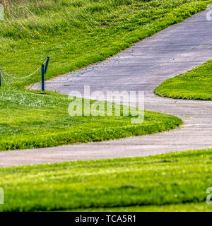 Cadre carré chemin pavé qui s'exécute sur une colline avec vue sur les herbes d'un vert d'une journée ensoleillée Banque D'Images