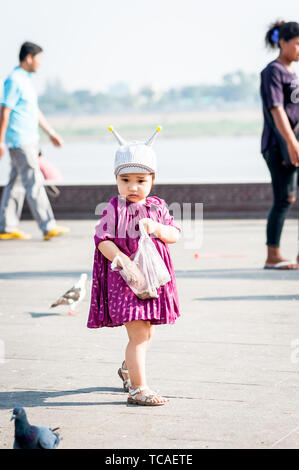 Une jolie petite fille alimente joyeusement les pigeons le long de la promenade de Phnom Penh, au Cambodge. Banque D'Images