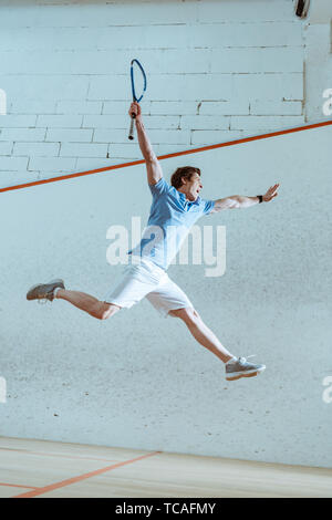 Sur toute la longueur de l'enthousiaste sportif de polo bleu sautant tout en jouant au squash Banque D'Images