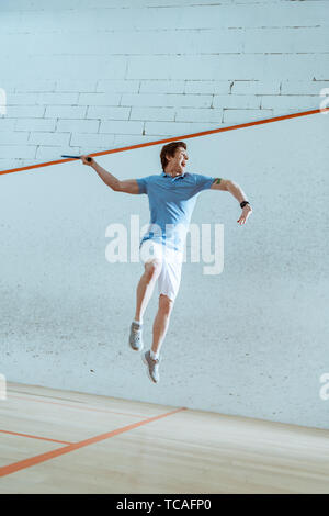 Sur toute la longueur de l'enthousiaste sportif de polo bleu sautant tout en jouant au squash Banque D'Images