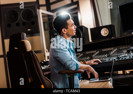 Handsome smiling mixed race producteur son travail en studio d'enregistrement à la console de mixage Banque D'Images