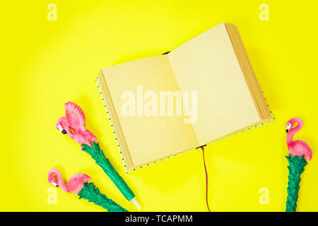 Desktop : flatlay avec stylo et papier couché flamingo rose vibrant fond jaune Banque D'Images