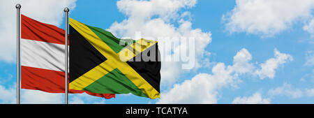 L'Autriche et de brandir le drapeau de la Jamaïque dans le vent contre ciel bleu nuageux blanc ensemble. Concept de diplomatie, de relations internationales. Banque D'Images