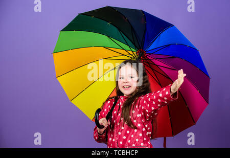 Protection contre la pluie. Arc-en-ciel. automne fashion. bonne petite fille avec parapluie colorés. cheerful hipster enfant dans l'humeur positive. Petite fille en imperméable. Prendre un peu de temps pour se reposer. Banque D'Images