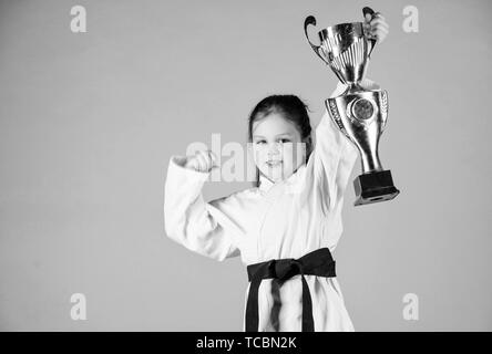 Le succès dans le sport de combat unique. pratiquer le Kung Fu. enfance heureuse. winner petite fille dans gi sportswear. Petite fille avec champion cup. arts martiaux et de l'énergie Activité pour les enfants. Trouver le poser. Banque D'Images