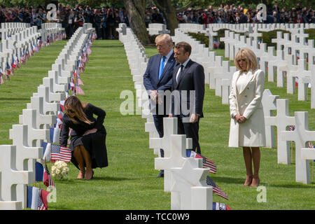 Première Dame des États-Unis Melania Trump met des fleurs sur la tombe d'un membre du service américain enterré au cimetière américain de Normandie en tant que président, Donald Trump/ Président français Emmanuel Macron et sa femme Brigitte Macron rechercher dans le cours d'une cérémonie marquant le 75e anniversaire du Jour J à la cimetière américain de Normandie le 6 juin 2019 à Colleville-sur-Mer, France. Des milliers de personnes ont convergé sur Normandie pour commémorer le 75e anniversaire de l'opération Overlord, l'invasion alliée DE LA SECONDE GUERRE MONDIALE connue sous le nom de D-Day. Banque D'Images