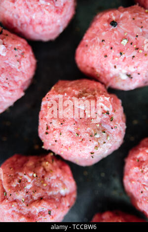 Boulettes de dinde non cuite brutes sur bac. viande hachée fraîche, poivre, sel Banque D'Images