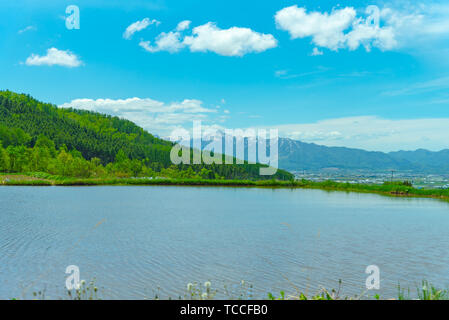 Grand ciel bleu et nuages blancs sur les terres agricoles de riz champ dans une belle journée ensoleillée au printemps. Vue panoramique du paysage rural avec des montagnes. Banque D'Images