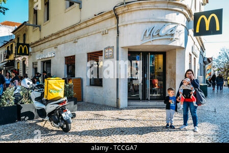 Cascais, Portugal - 5 juin 2019 : Glovo coursiers livraison sur moto et vélo près de la chaîne McDonald's restaurant. Glovo espagnol célèbre service de livraison Banque D'Images