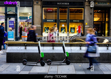 Les gens passent devant la chaux des scooters électriques à gauche prêt à embaucher dans une rue commerçante animée à Vienne le 04/11/2018. Photo par Julie Edwards Banque D'Images