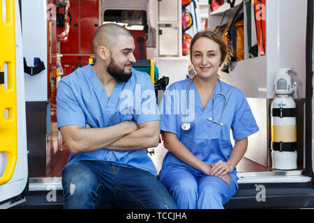 Portrait de deux ambulanciers positif assis en voiture ambulance Banque D'Images