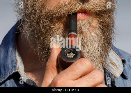 Homme barbu tenant une pipe dans sa bouche, close-up Banque D'Images