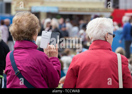Les femmes âgées debout alors que l'on prend une photo à l'aide de son téléphone portable ou un téléphone cellulaire Banque D'Images