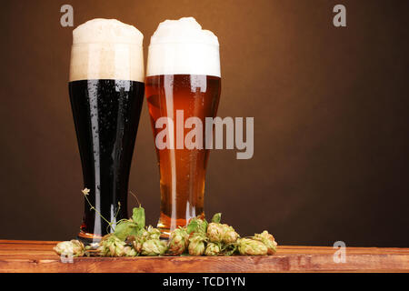 D'or noir et de la bière dans des verres et hop sur la table en bois sur fond brun Banque D'Images