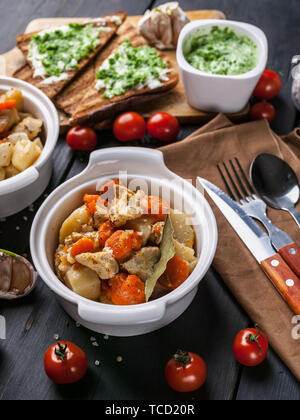 Close-up du poulet avec des pommes de terre et les carottes, des sandwichs au fromage et tomates cerises sur un fond de bois sombre. Banque D'Images