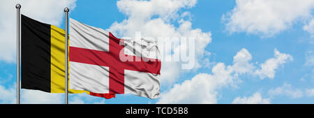 La Belgique et l'Angleterre drapeaux dans le vent contre ciel bleu nuageux blanc ensemble. Concept de diplomatie, de relations internationales. Banque D'Images
