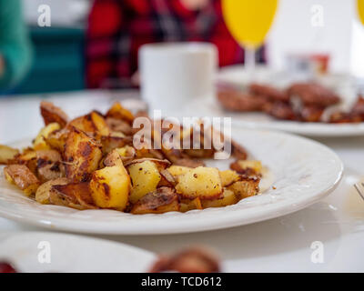 Close up of American traditionnelle assiette petit-déjeuner de pommes de terre, saucisses, bacon sur une table à manger avec petit-déjeuner complet propagation Banque D'Images